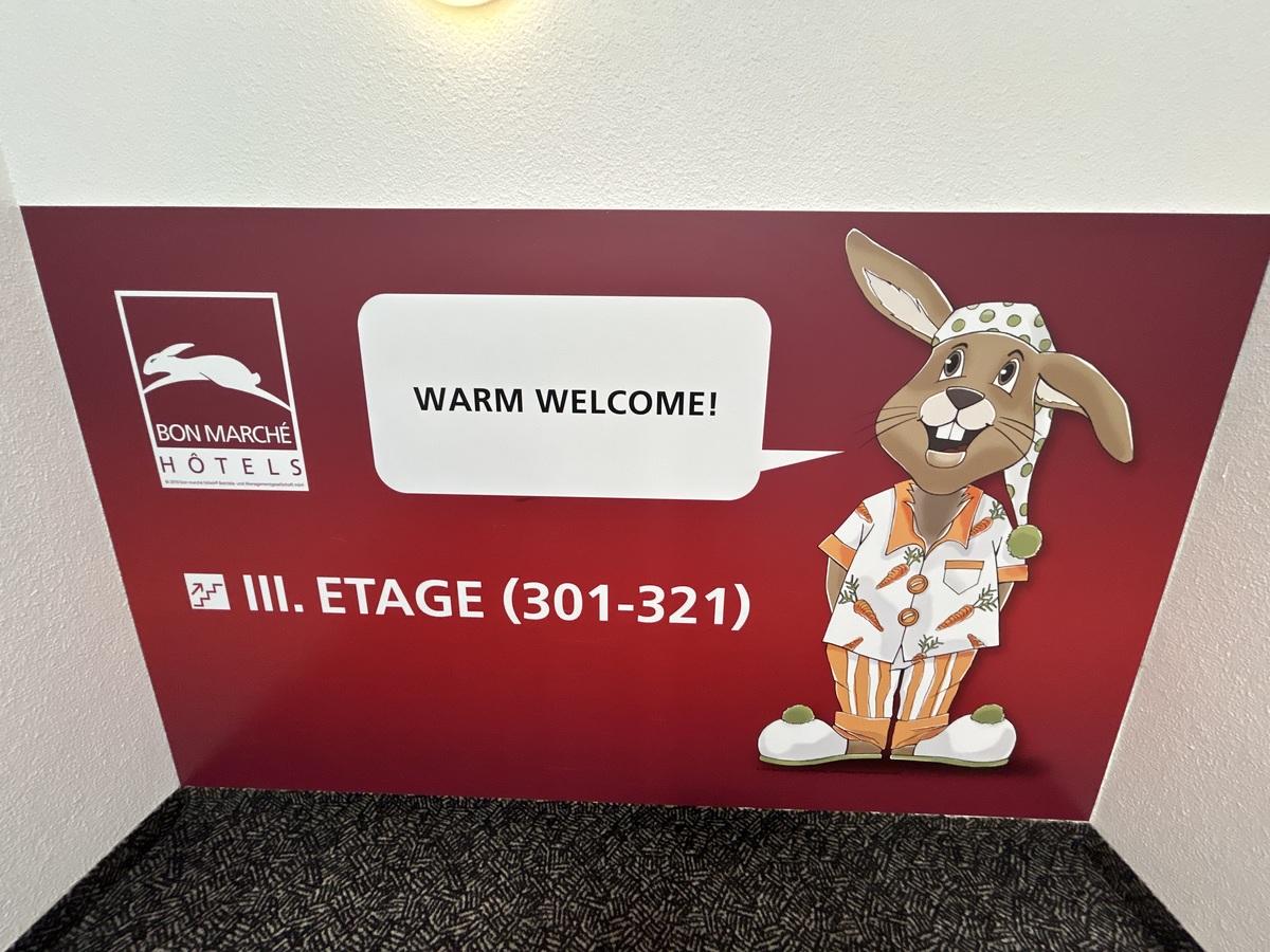 Ein brauner Hase im Schlafanzug lächelt freundlich vor rotem Hintergrund