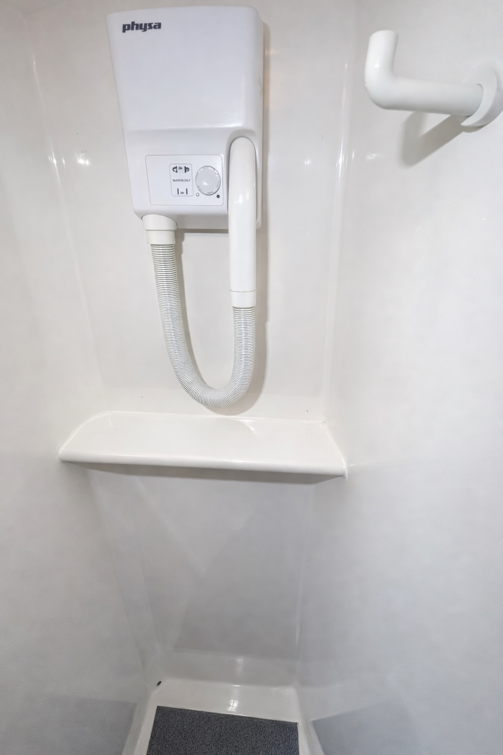 Weißes elektrisches Duschgerät mit Schlauch und Haken vor hellen Wänden