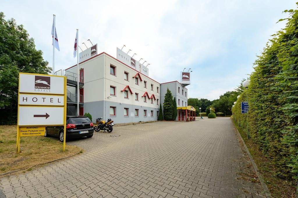 Modern dreistöckiges Hotel mit weißer Fassade, roten Fensterläden und Parkplatz