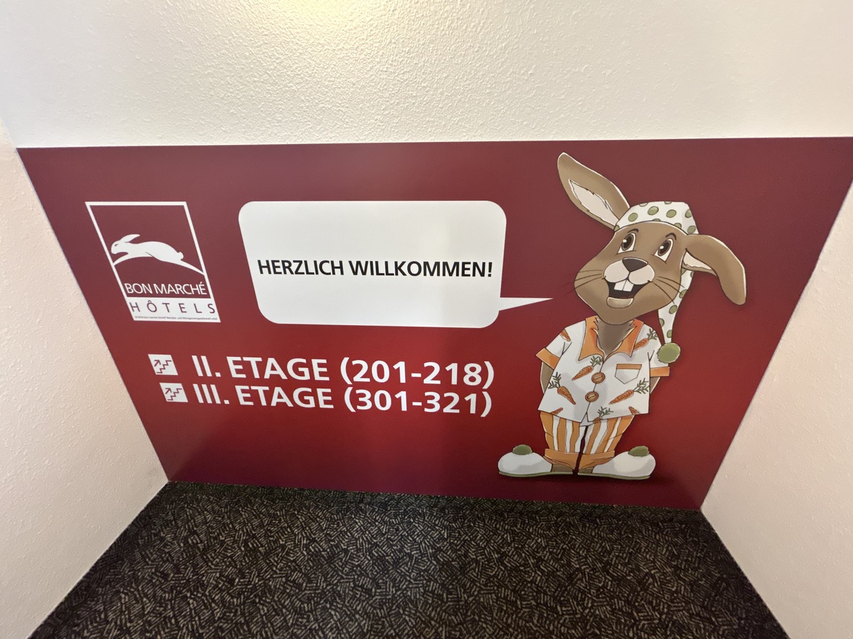 Ein freundlicher gezeichneter Hase lacht auf rotem Hintergrund und trägt Pyjama