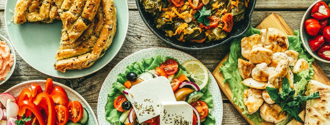 Selection of traditional greek food - salad, meze, pie, fish, tzatziki, dolma on wood background, top view