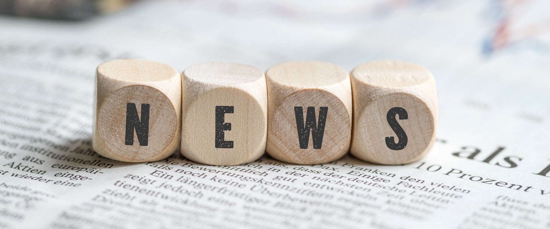 Würfel mit dem Wort "NEWS" auf einer Zeitung