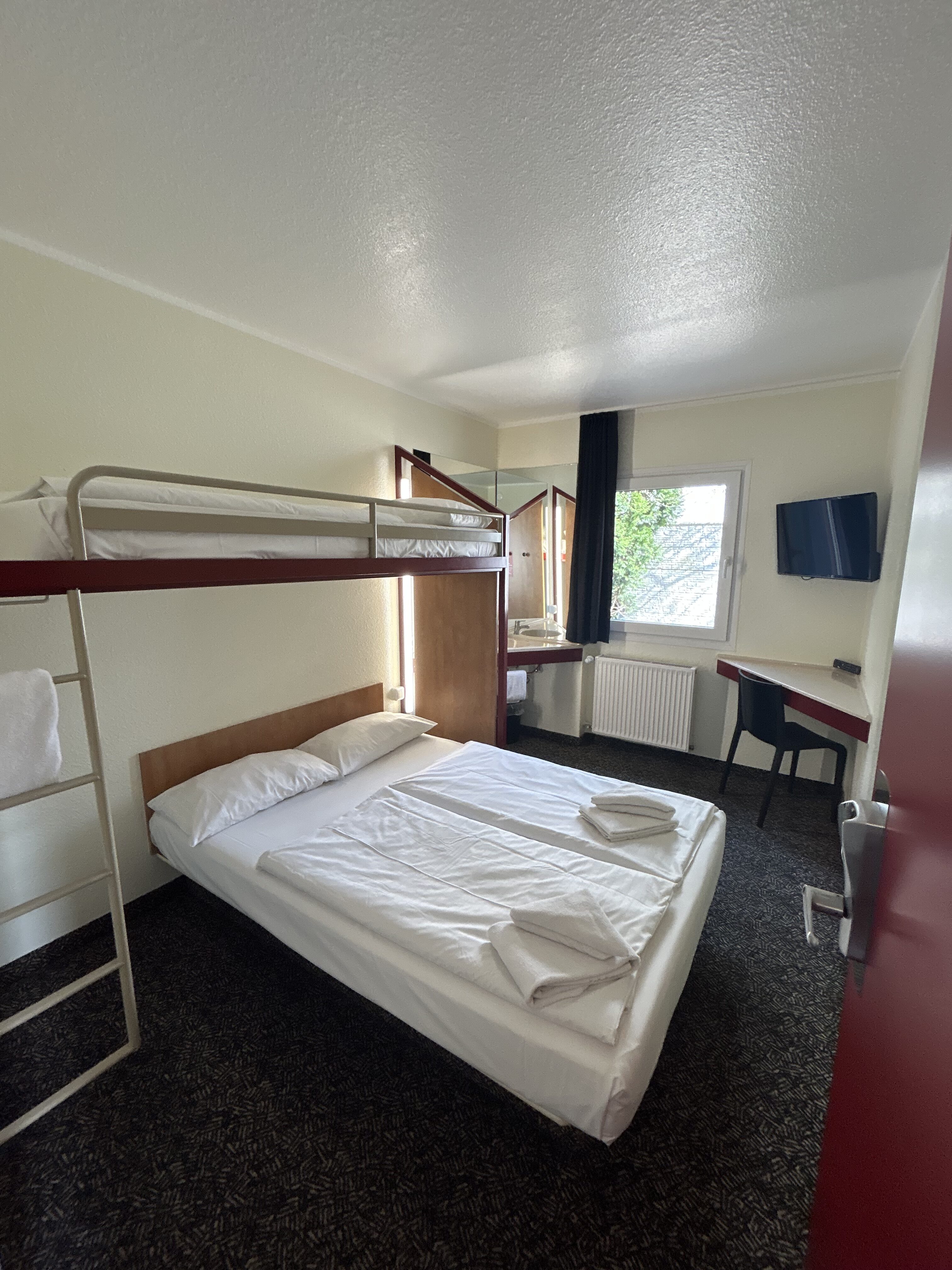 Kleines Zimmer mit Doppelbett und Etagenbett in Weiss und Rot, ordentlich